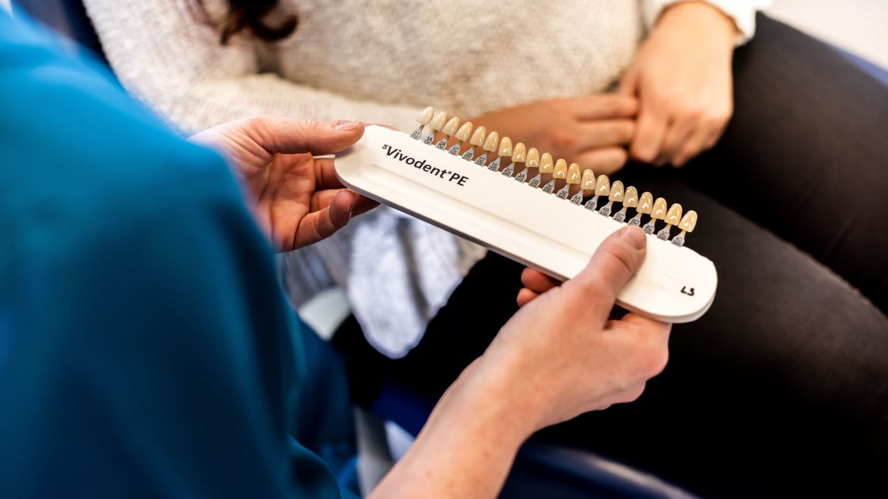 Dentist fitting a denture and checking the fit with a patient