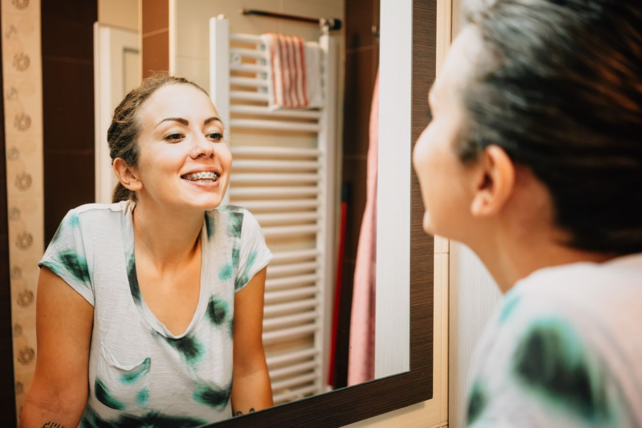 Patient looking at her fixed dental braces in the mirror