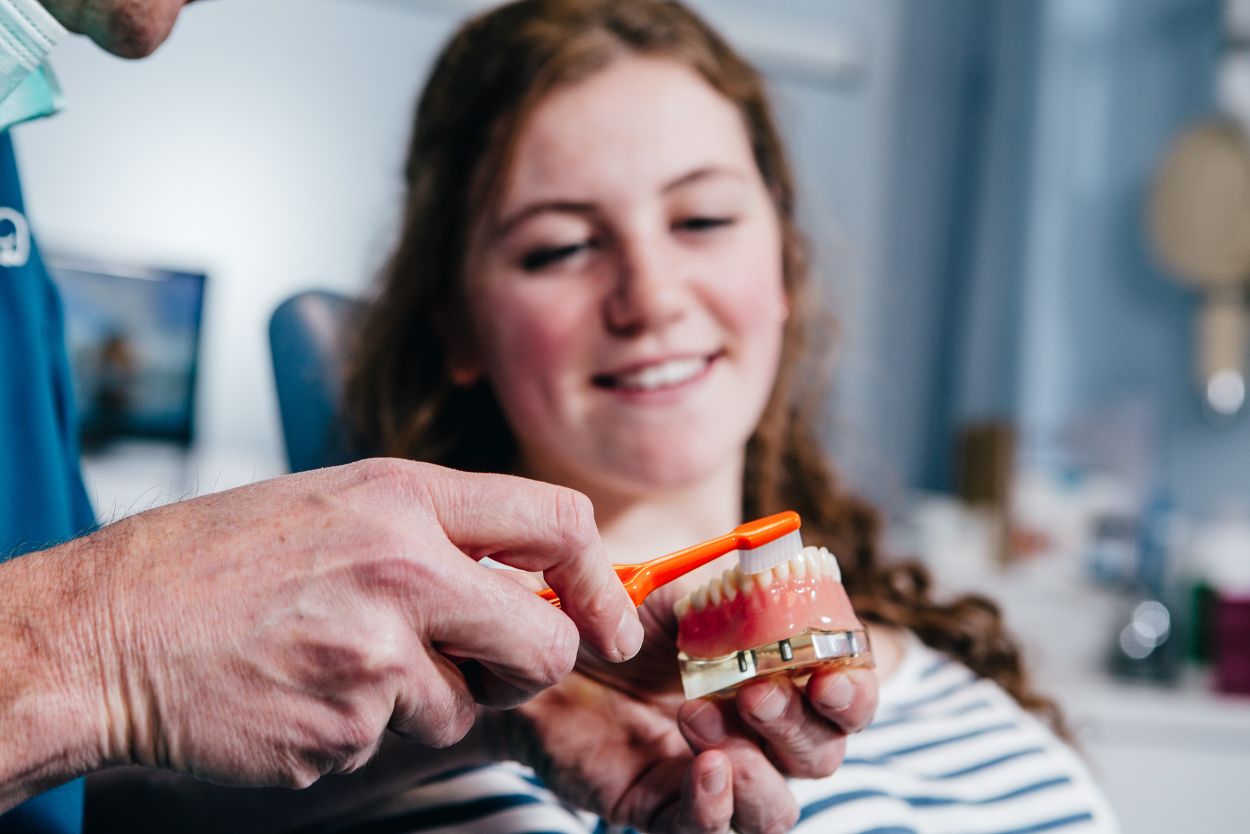 Dentist demonstrating correct toothbrushing technique to a patient during a dental hygiene appointment