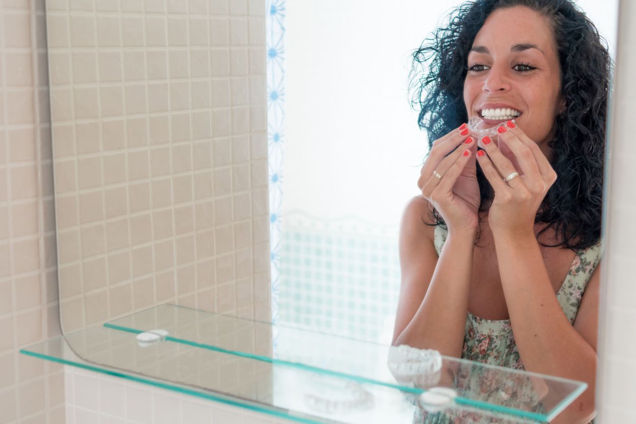 Patient holding a clear Invisalign aligner used to straighten teeth